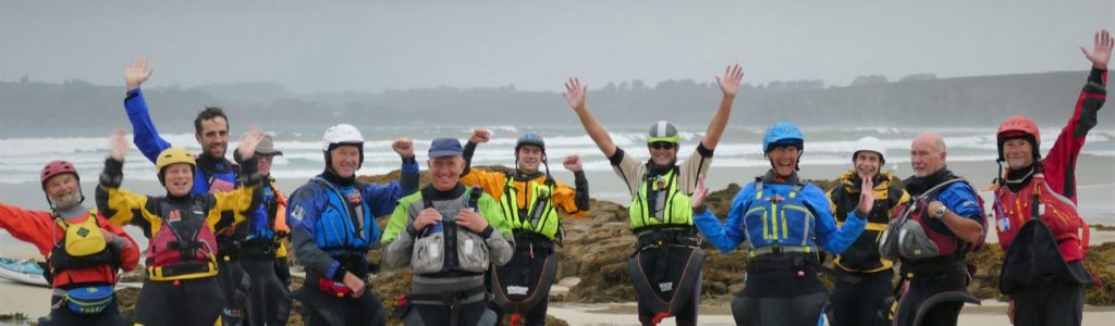 happy sea kayakers on Brittany beach with arms up